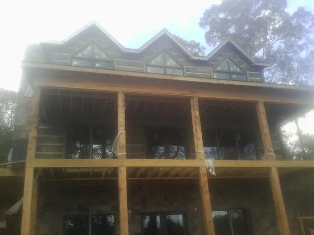 Dormers and porch framing on a large log home under construction — Roof Coating work by our crew in Remsenburg
