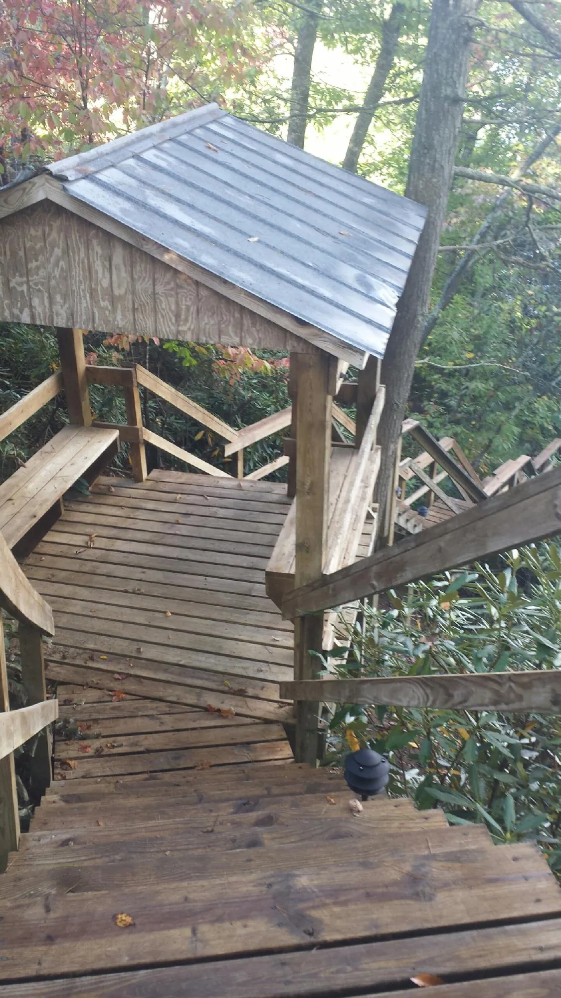 Metal roofed shelter over wooden steps on a wooded walkway — Skylight Repair & Installation work by our crew in Remsenburg
