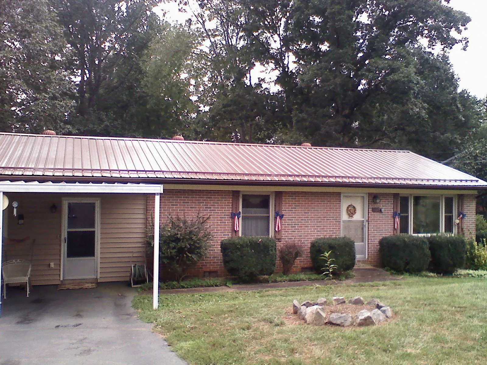 Bronze metal roof and carport on a brick ranch home — Roof Repair work by our crew in Remsenburg
