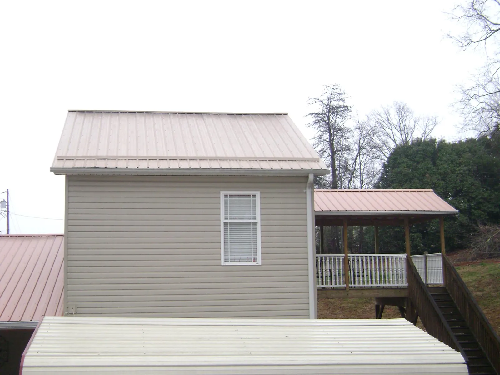 Tan metal roofs on a two story addition and attached porch, from a Roof Replacement job in Remsenburg