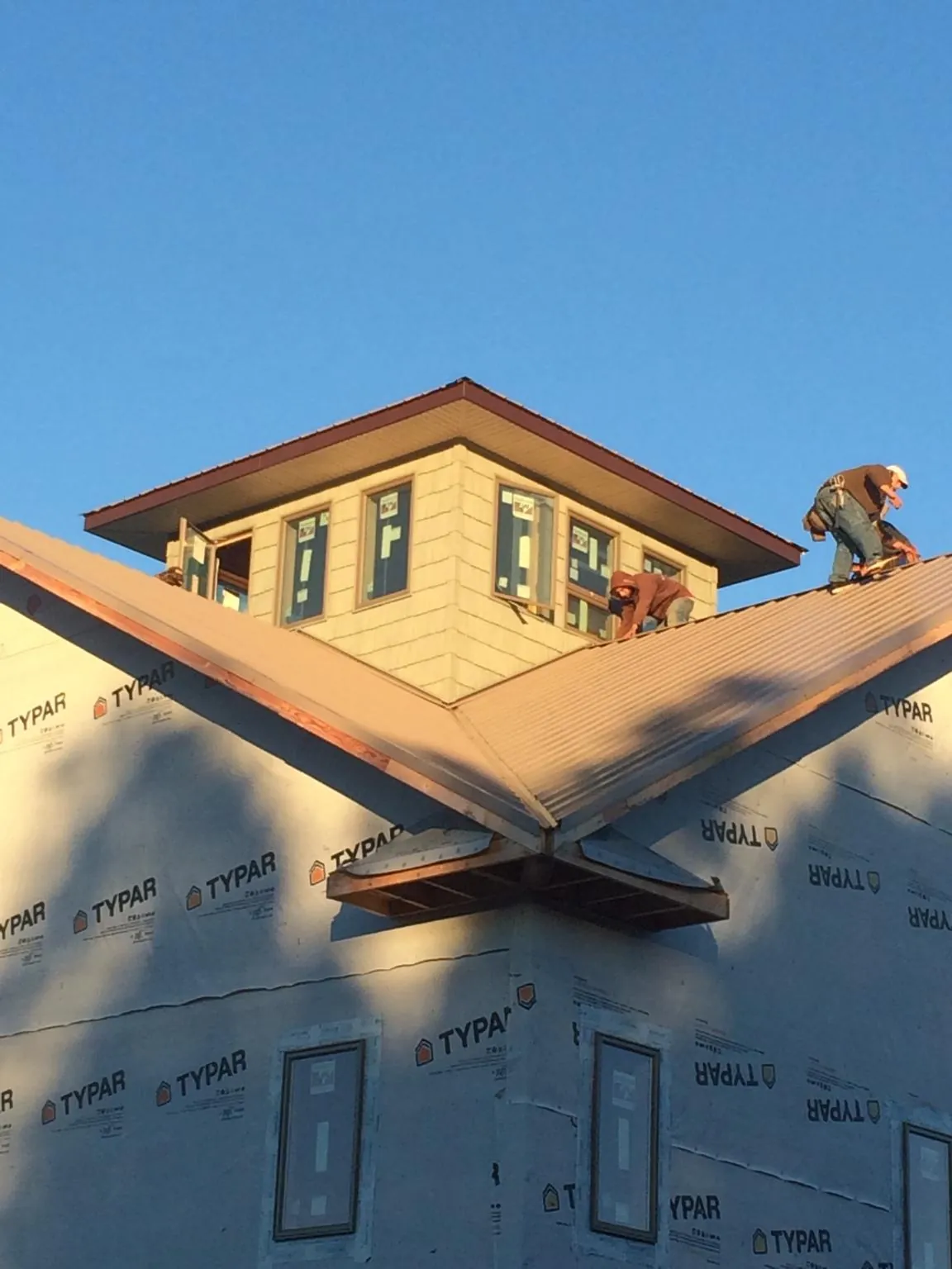 Roofers working around a rooftop cupola on a new metal roof at sunset — Roof Waterproofing in Remsenburg by Roofing Brothers